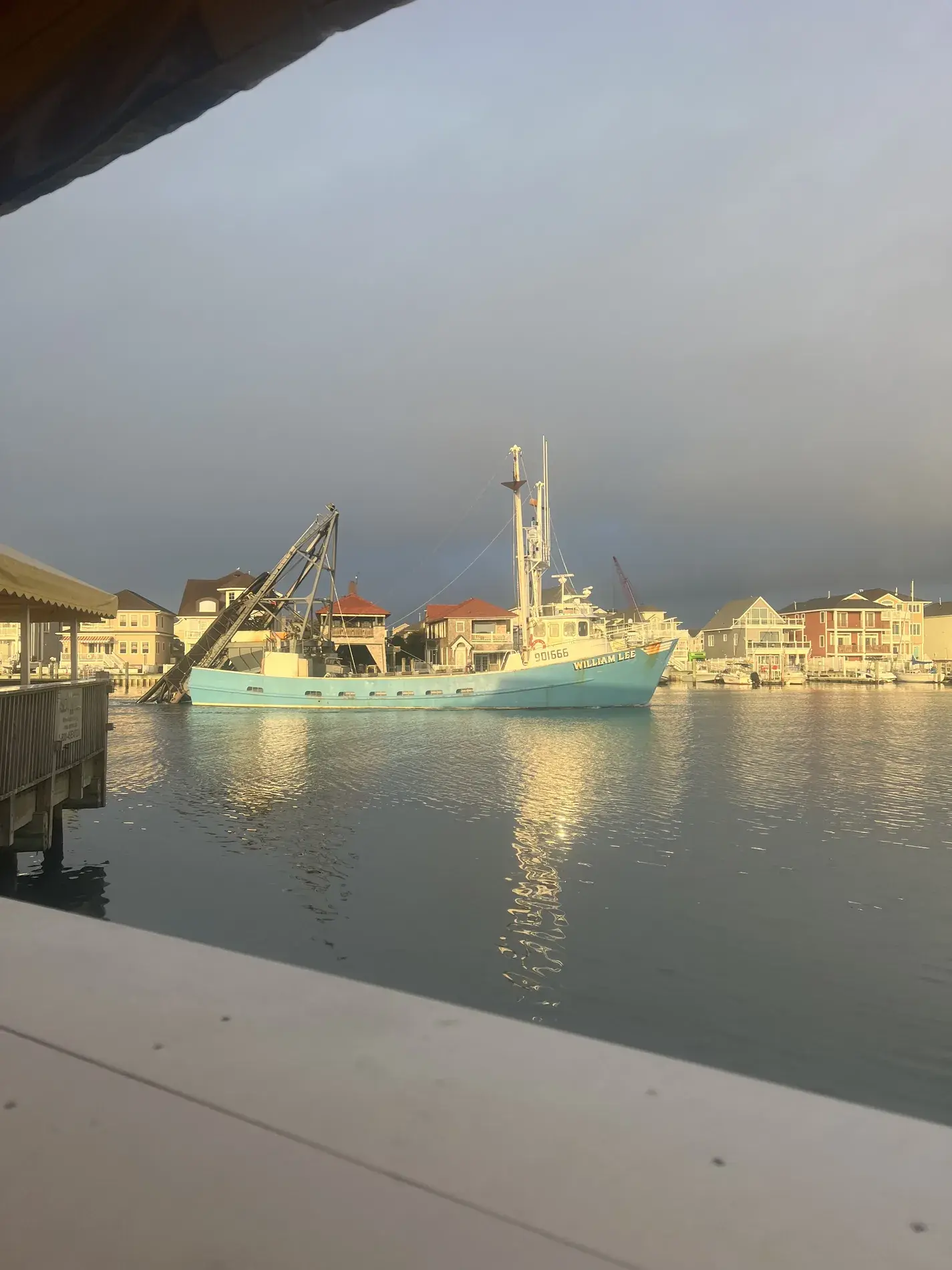 Working boat in a coastal shore harbor with waterfront homes
